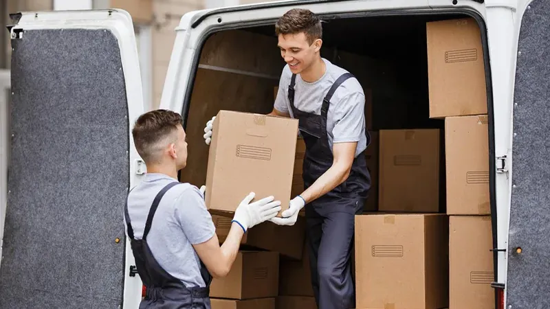 Operarios de mudanza cargando cajas embaladas en una camioneta antes de un viaje internacional
